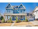Charming two-story blue home featuring a welcoming front porch with stone columns and manicured landscaping at 520 Crawfish Dr, Fort Mill, SC 29708
