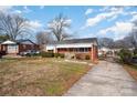 Traditional brick home with mature trees, long driveway, and attached carport at 1438 Waddell St, Charlotte, NC 28216