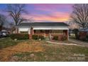 Charming brick home featuring awning-covered windows under a colorful sky at dusk at 1438 Waddell St, Charlotte, NC 28216