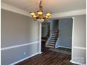 Dining area with an elegant chandelier, crown molding, and wood-look flooring at 5934 Hickory Hollow Ct, Harrisburg, NC 28075