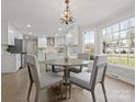 Bright dining area with chandelier, bay window, and open access to a modern white kitchen at 122 Lansdowne Rd, Charlotte, NC 28270