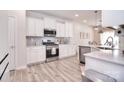 This modern kitchen boasts stainless steel appliances, white cabinets, and wood-look flooring at 124 Doncaster Dr, Mooresville, NC 28115