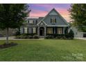 Gray two-story house with stone accents, landscaping, and a three-car garage at dusk at 1320 Torrens Dr, Wesley Chapel, NC 28110
