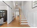 Spacious foyer with hardwood floors, white wainscoting, staircase and modern chandelier at 831 Naples Dr, Davidson, NC 28036