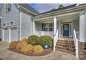 Inviting covered front porch with stylish railings, brick steps, and manicured landscaping at 11419 Rising Star Ct, Charlotte, NC 28215