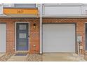 Townhome entrance featuring a brick facade, gray front door, garage, and modern lighting at 3617 Vallette Ct, Charlotte, NC 28203