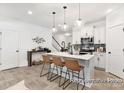Modern kitchen with white cabinets, island with seating, stainless steel appliances, and gray backsplash at 11311 Magpie Ct # 2, Charlotte, NC 28215