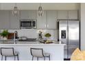 Bright kitchen boasts stainless steel appliances, gray cabinetry, herringbone backsplash, and stylish pendant lights at 4114 Lattistep Ln, Charlotte, NC 28269