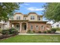 Inviting front exterior featuring a brick facade, stone accents, covered porch, and a lush lawn at 14507 Old Vermillion Dr, Huntersville, NC 28078