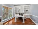 Bright home office with built-in bookshelves, geometric wallpaper, and large windows overlooking the yard at 14507 Old Vermillion Dr, Huntersville, NC 28078