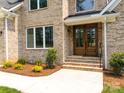 Charming home entrance featuring a beautiful wood door, brick steps, and lush landscaping at 2418 Lexington Approach Dr, Charlotte, NC 28262