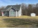 View of the backyard with green grass and a small storage shed and gray home at 281 Fair Acres Ln, Taylorsville, NC 28681