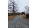 Quaint one-story brick home with a long gravel driveway and mature trees at 32269 Pennington Rd, Albemarle, NC 28001