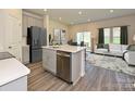 Modern kitchen with gray cabinetry, stainless steel appliances, island sink, and open layout to the living area at 5014 Kellaher Pl, Charlotte, NC 28216