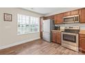 Well-lit kitchen featuring stainless steel appliances, wood cabinets, and durable wood flooring at 610 John St, Monroe, NC 28110