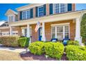 Inviting front porch with classic columns, complemented by neatly trimmed shrubs and an American flag at 658 Quicksilver Trl, Fort Mill, SC 29708