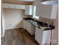 Bright kitchen featuring white cabinets, dark countertops, a stainless steel sink, and durable laminate flooring at 67 Travora Cir, York, SC 29745