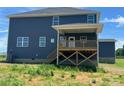 Rear view of a two-story home with a covered porch, deck, and backyard with a gentle slope at 1459 Mocksville Hwy # 19, Statesville, NC 28625