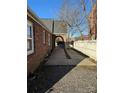 Property's side view shows a long driveway with a gated entrance and a brick wall, leading to the backyard at 2220 The Plz, Charlotte, NC 28205