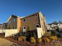 Back exterior of cozy two-story townhome showcasing fencing, trimmed greenery, and partial stone exterior on a sunny day at 9020 Northfield Crossing Dr, Charlotte, NC 28269