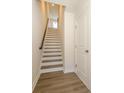 Bright staircase featuring wood-look flooring, white risers and a dark wood handrail at 1311 Cerium Way, Charlotte, NC 28211