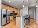 Modern kitchen with stainless steel appliances, wood cabinets, and a granite countertop breakfast bar at 210 N Church St # 3606, Charlotte, NC 28202
