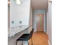 Compact kitchenette featuring a granite countertop bar with a black leather stool and hardwood floors at 210 N Church St # 3606, Charlotte, NC 28202