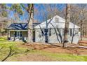 Side view of a gray brick house with a cozy porch, set amongst mature trees, showing the home's unique architecture at 2478 Stribling Cir, Lancaster, SC 29720