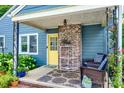 Inviting covered porch with wicker chairs, patterned rug, brick accents, and yellow front door at 968 Waverly Ave, Rock Hill, SC 29730