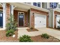 A welcoming townhome entrance with a brick facade, black door and one car garage at 4242 Black Ct # 233, Harrisburg, NC 28075