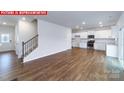Spacious living room features hardwood floors, white walls, staircase, and connects to the kitchen and front door at 11204 Cardinal Creek Ave, Charlotte, NC 28215