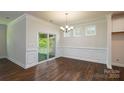 Bright dining room showcasing dark hardwood floors, paneled walls, large sliding glass doors, and elegant lighting at 119 Noah Ln, Troutman, NC 28166