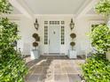 Inviting front porch featuring a blue door, potted plants, and classic white rocking chairs at 2109 Wellesley Ave, Charlotte, NC 28207