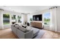 Inviting living room with a gray sectional sofa, large windows, and sleek modern entertainment center at 2243 Cobble Ct # 222, Monroe, NC 28110