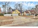 Inviting single-story yellow home with a spacious driveway, complemented by mature trees and landscaping at 2321 Heathershire Ln, Matthews, NC 28105