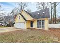 Lovely yellow home with a white garage door, large windows, and a cozy entrance at 2321 Heathershire Ln, Matthews, NC 28105