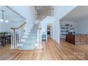 Bright foyer with hardwood floors, a staircase with white railing, and an adjacent office with built-in shelves at 2800 Providence Hills Dr, Matthews, NC 28105