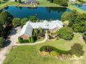 A captivating aerial view of a brick home featuring a lush landscaped yard and a serene lake backdrop at 6823 Manatee Dr, Concord, NC 28025