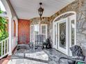 Inviting front porch with stone accents, rocking chairs, and elegant lighting, creating a cozy outdoor space at 6823 Manatee Dr, Concord, NC 28025