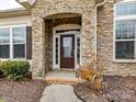 Close-up of front door featuring elegant stone archway, sidelights, and decorative hardware at 10094 Dressage Ln, Midland, NC 28107