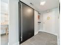 Modern hallway features gray tiled floors and a black sliding door near the kitchen at 1300 Reece Rd # 201, Charlotte, NC 28209