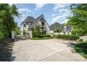 Gated entrance with a long driveway leading to a white brick home with manicured landscaping at 1328 S Kings Dr, Charlotte, NC 28207