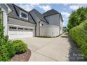 Spacious driveway with a view of the house, featuring lush landscaping and a three-car garage at 1328 S Kings Dr, Charlotte, NC 28207