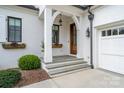Inviting front porch with a wooden front door, decorative flower boxes, and charming lighting fixtures at 1328 S Kings Dr, Charlotte, NC 28207