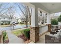 Inviting front porch with brick accents, white columns, hanging lanterns, and comfortable seating at 17436 Harbor Walk Dr, Cornelius, NC 28031