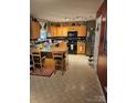 Classic kitchen boasting wood cabinets, black appliances, a granite island, and checkered backsplash detailing at 10415 Plantain Ct, Charlotte, NC 28213