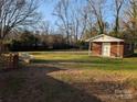 A building with a covered porch sits in a flat grassy back yard enclosed with a brick retaining wall at 1807 Brantley Rd, Kannapolis, NC 28083