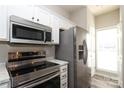 Well-equipped kitchen with stainless steel appliances, modern white cabinets and a bright window at 14713 Lions Pride Ct, Charlotte, NC 28273