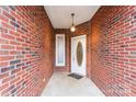 Close up on the home's front porch and front door with sidelight, showing the brick wall and overhead lighting at 2323 Pinefield Ct, Gastonia, NC 28056