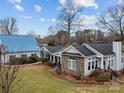 Charming home featuring stone accents, grey siding and a metal roof, nestled in a lush, landscaped yard at 246 Apache Rd, Troutman, NC 28166